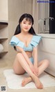 A woman in a blue bikini sitting on a white rug.