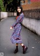 A woman in a floral dress is walking down the street.