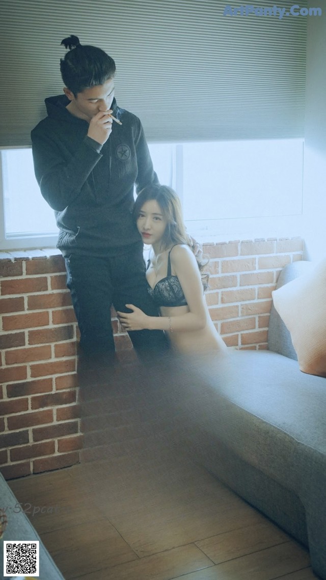 A man and a woman sitting on a couch smoking a cigarette.