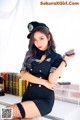 A woman in a police uniform sitting on a desk.