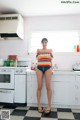 A woman standing in a kitchen next to a stove.