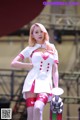 A woman in a white and pink outfit standing on a stage.