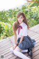 A woman in a school uniform sitting on a wooden deck.