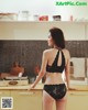 A woman in a black lingerie standing in a kitchen.