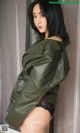 A woman in a green leather jacket is posing for a picture.