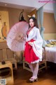 A woman in a red and white dress holding an umbrella.