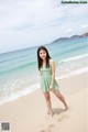 A woman in a green dress standing on a beach.