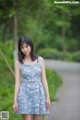 A woman in a blue dress standing on a dirt road.