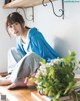 A woman sitting on top of a wooden table next to a plant.